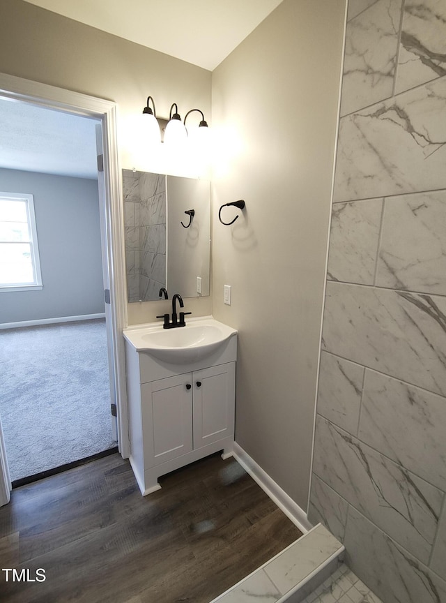 bathroom featuring baseboards, wood finished floors, and vanity