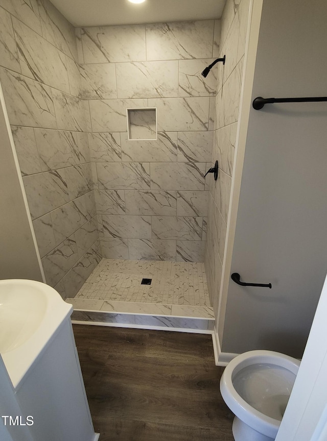 bathroom featuring wood finished floors, a shower stall, and toilet