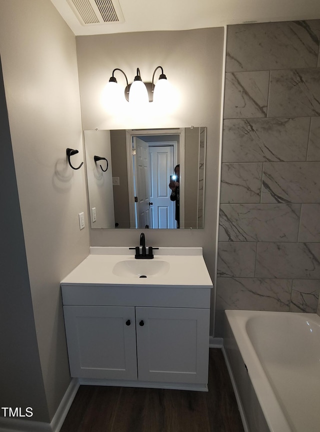 full bath with wood finished floors, vanity, visible vents, and baseboards