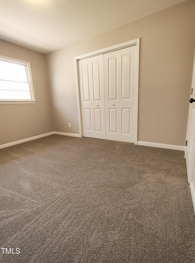 unfurnished bedroom with a closet, baseboards, and carpet flooring