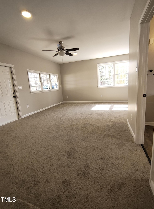 carpeted spare room featuring baseboards and a ceiling fan