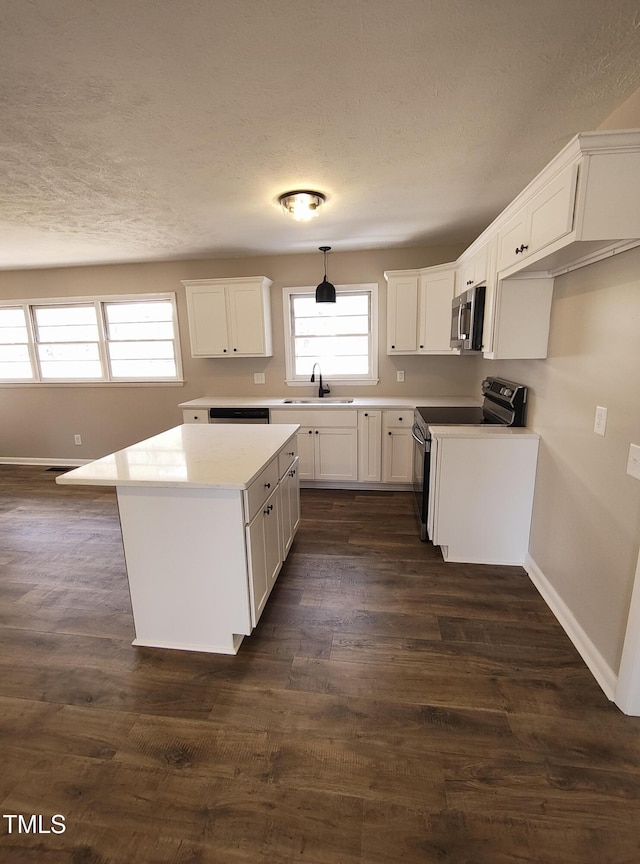 kitchen with stainless steel microwave, dark wood-style flooring, a center island, a sink, and range with electric stovetop