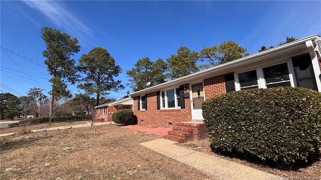 view of property exterior with crawl space and brick siding