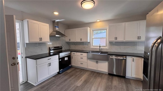 1809 Wayne Ln, Fayetteville, NC 28304 - kitchen with dark wood-style floors, dark countertops, appliances with stainless steel finishes, a sink, and wall chimney range hood