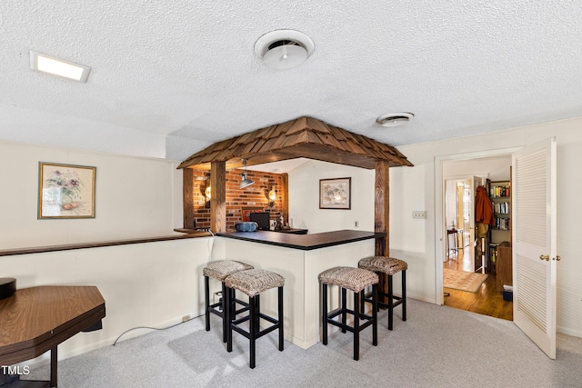 bar featuring a dry bar, a textured ceiling, visible vents, and carpet flooring