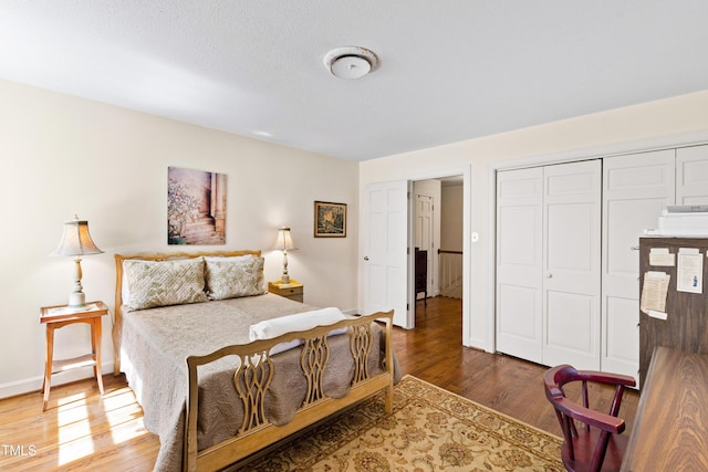 bedroom with a closet, baseboards, and wood finished floors