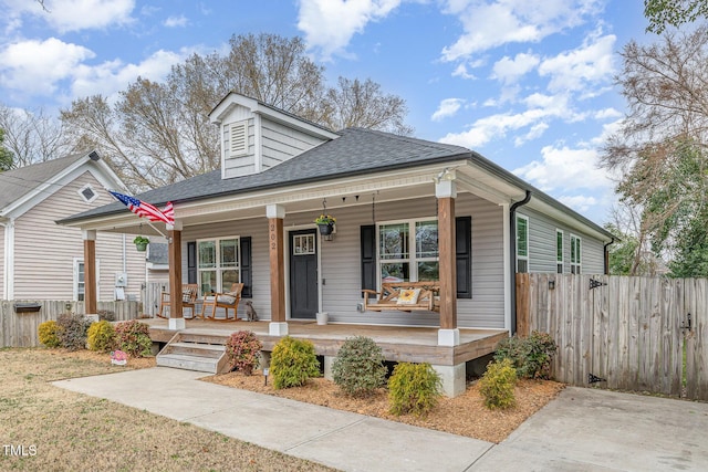 view of front of home with a shingled roof, fence, and a porch