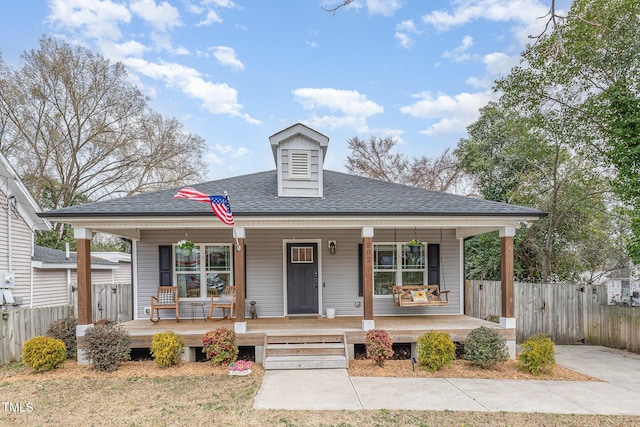 bungalow with fence, a porch, and roof with shingles