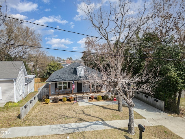 view of front of house with a front lawn, roof with shingles, fence, and a wooden deck