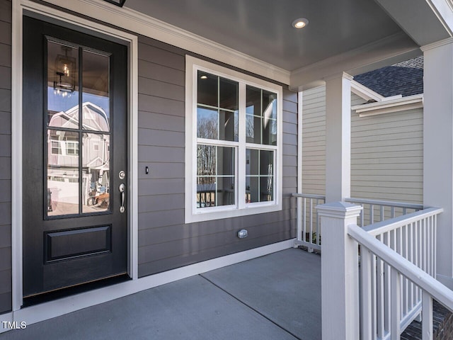 doorway to property featuring covered porch and roof with shingles