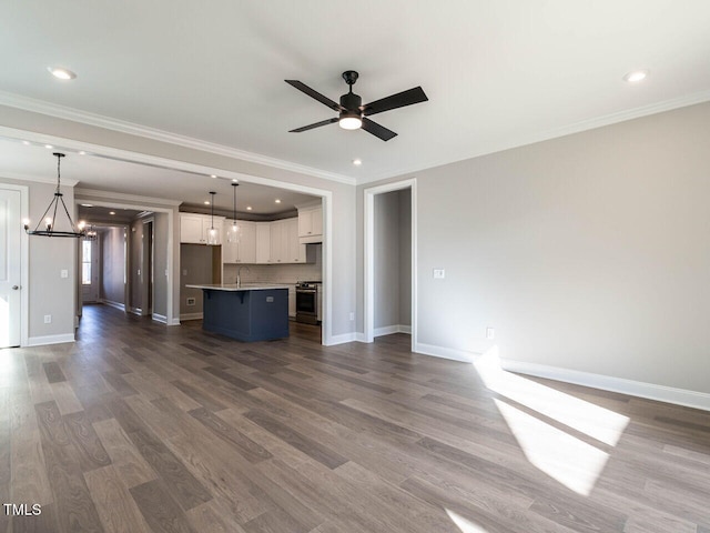 unfurnished living room featuring ceiling fan with notable chandelier, dark wood-type flooring, and crown molding