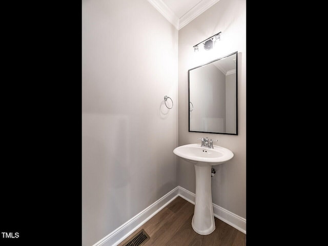 bathroom with baseboards, wood finished floors, visible vents, and crown molding