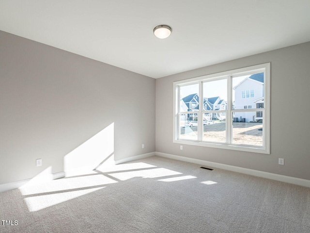 empty room featuring carpet floors, baseboards, and visible vents