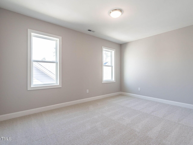 empty room featuring light colored carpet and baseboards