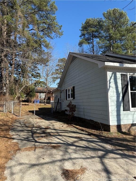 view of home's exterior featuring aphalt driveway, crawl space, and fence