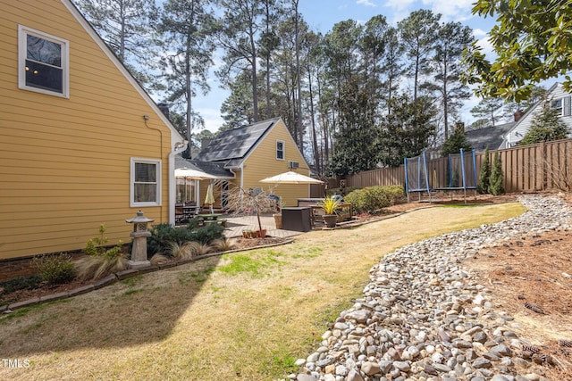 view of yard featuring a trampoline, fence, and a patio