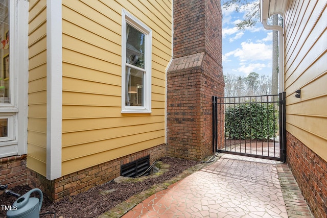 view of home's exterior with crawl space and a gate