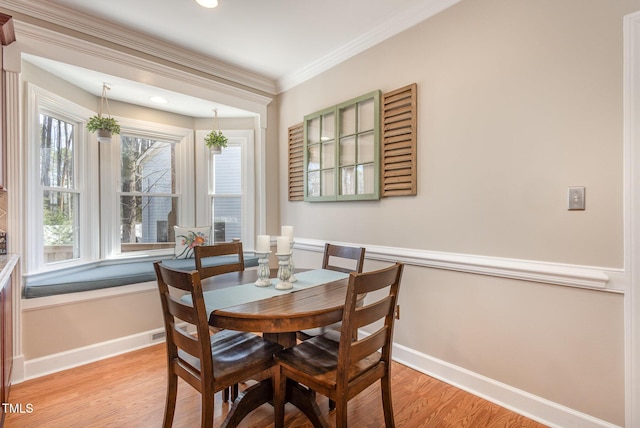 dining area featuring ornamental molding, light wood-type flooring, and baseboards