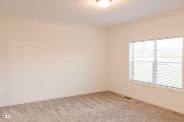 empty room featuring visible vents, crown molding, light carpet, and baseboards