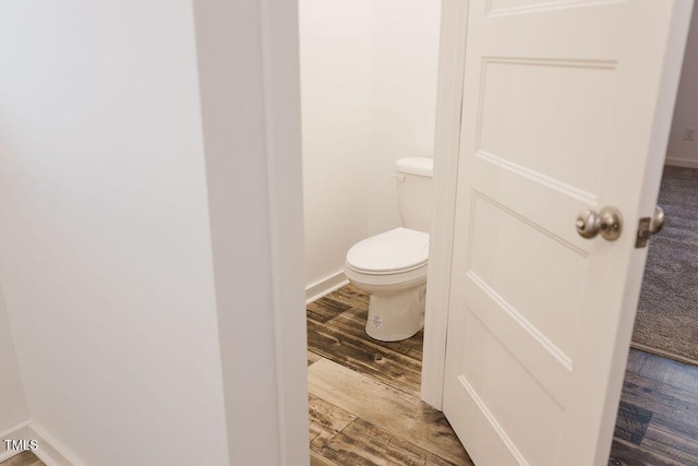 bathroom with baseboards, toilet, and wood finished floors