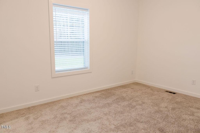 carpeted spare room with visible vents and baseboards