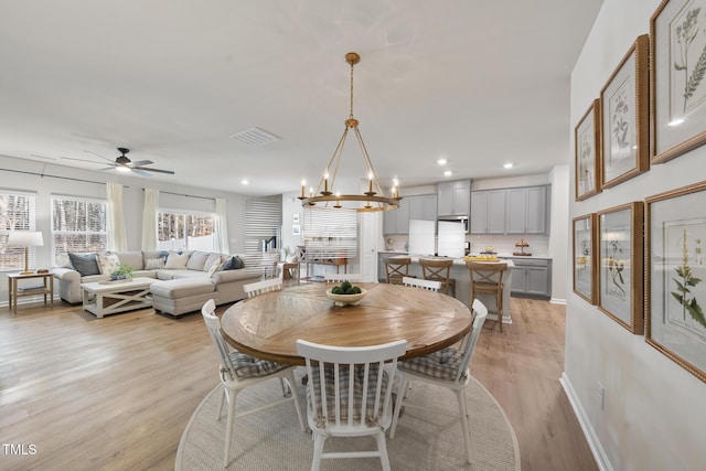 dining space with light wood-style floors, ceiling fan with notable chandelier, visible vents, and recessed lighting