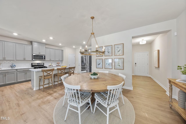 dining space featuring recessed lighting, light wood-type flooring, an inviting chandelier, and baseboards