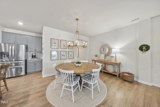 dining room with a notable chandelier, light wood-style flooring, and baseboards