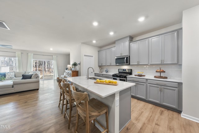 kitchen with a kitchen breakfast bar, stainless steel appliances, light stone countertops, and gray cabinetry