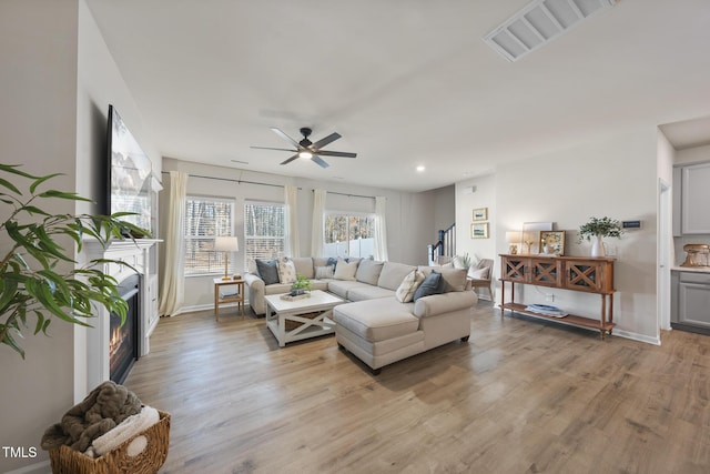 living room with recessed lighting, visible vents, light wood-style flooring, a ceiling fan, and baseboards