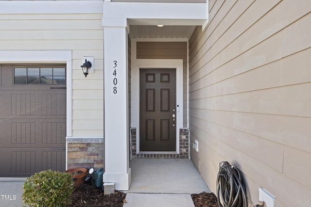 entrance to property featuring a garage and stone siding