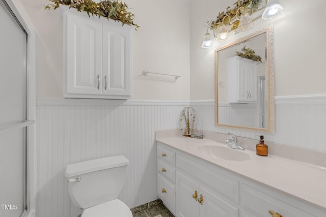 bathroom with toilet, vanity, and wainscoting