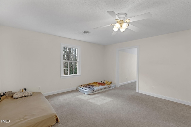 carpeted bedroom with a textured ceiling, a ceiling fan, visible vents, and baseboards