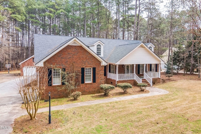 view of front facade with driveway, covered porch, a front yard, and brick siding