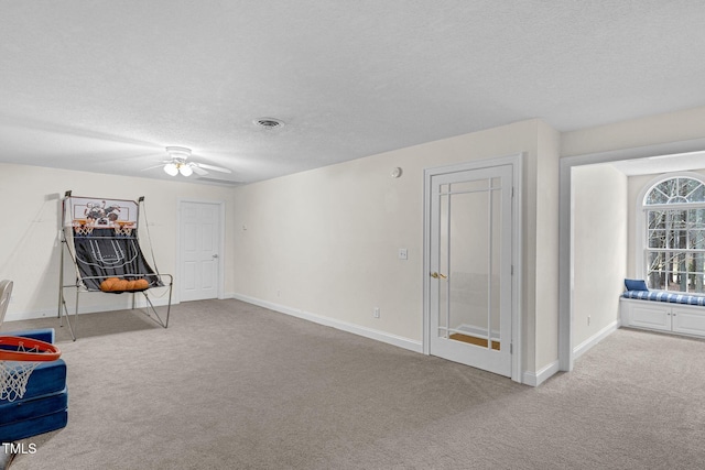 interior space featuring carpet, visible vents, a textured ceiling, and baseboards