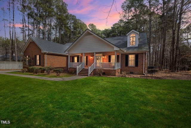 view of front of property featuring crawl space, covered porch, a front yard, and brick siding