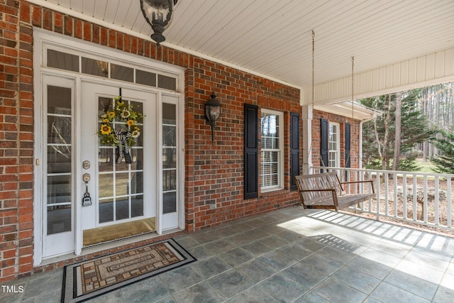 property entrance with a porch and brick siding