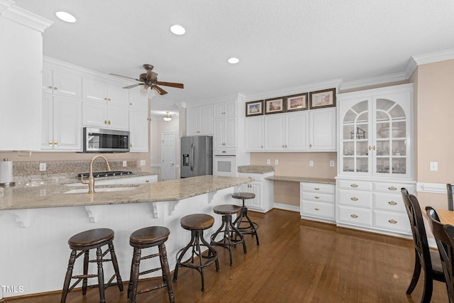 kitchen with stainless steel appliances, dark wood-style flooring, a peninsula, and white cabinetry