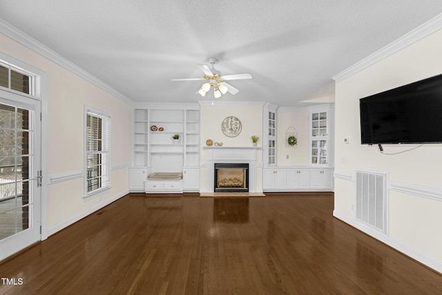 unfurnished living room with a fireplace with raised hearth, a textured ceiling, wood finished floors, visible vents, and crown molding