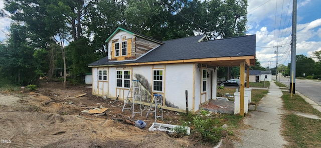 exterior space with a shingled roof and stucco siding