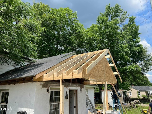 exterior space with roof with shingles and stucco siding