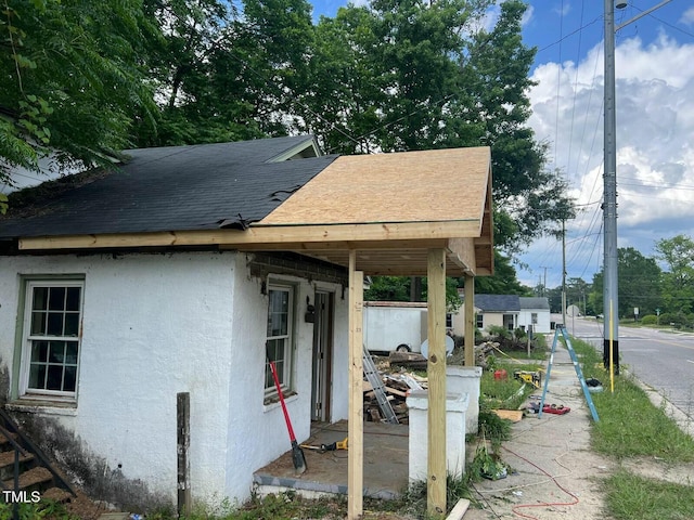 view of side of home featuring a shingled roof and stucco siding