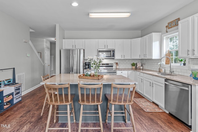 533 E Maple Ave, Holly Springs, NC 27540 - kitchen with stainless steel appliances, white cabinets, a kitchen island, light stone countertops, and recessed lighting