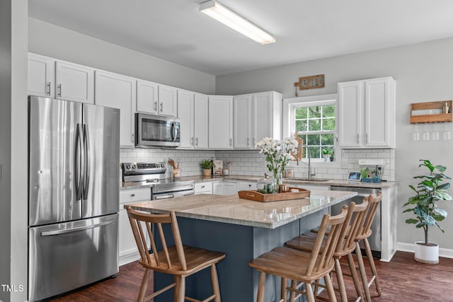 533 E Maple Ave, Holly Springs, NC 27540 - kitchen with stainless steel appliances, a breakfast bar area, dark wood-style floors, and white cabinetry