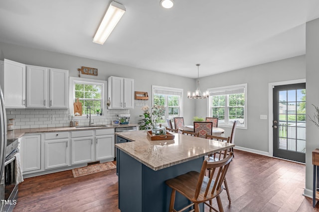 533 E Maple Ave, Holly Springs, NC 27540 - kitchen with a breakfast bar area, white cabinetry, a center island, and dark wood finished floors