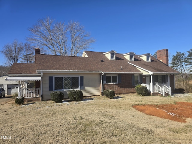 rear view of house with a porch, a shingled roof, brick siding, a yard, and a chimney