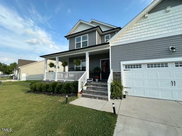 view of front of property featuring driveway, a garage, a porch, and a front yard