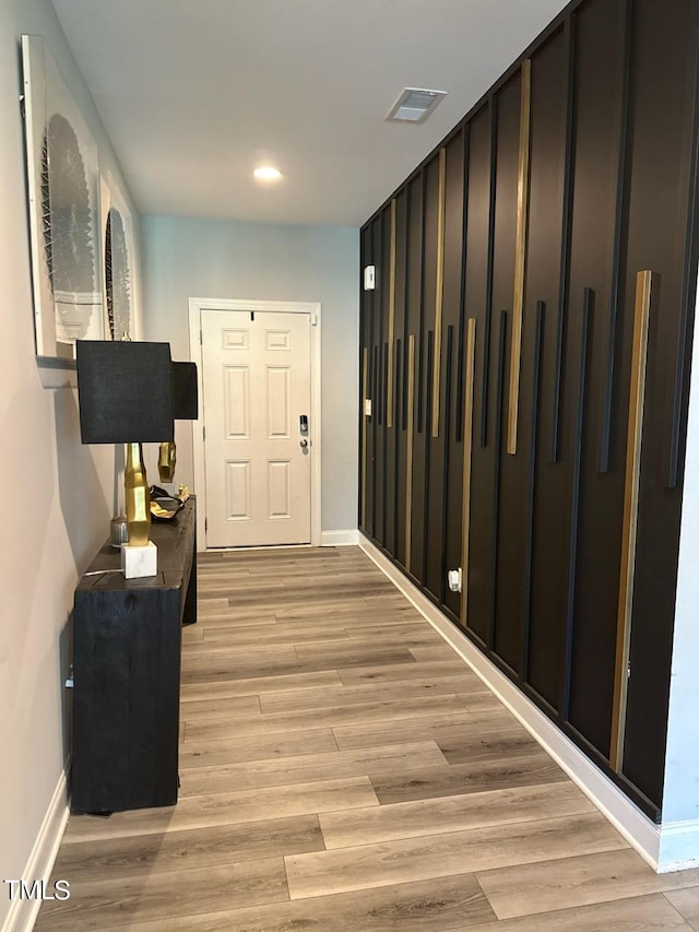 corridor featuring light wood finished floors, recessed lighting, visible vents, and baseboards