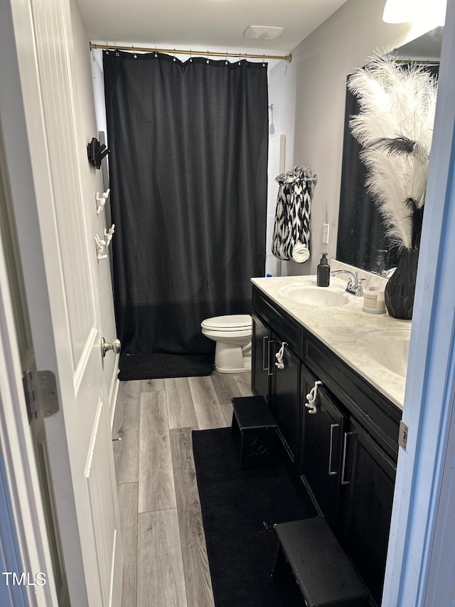 bathroom with vanity, wood finished floors, toilet, and a shower with curtain