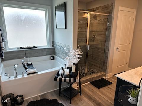 bathroom with a bath, plenty of natural light, a shower stall, and wood finished floors